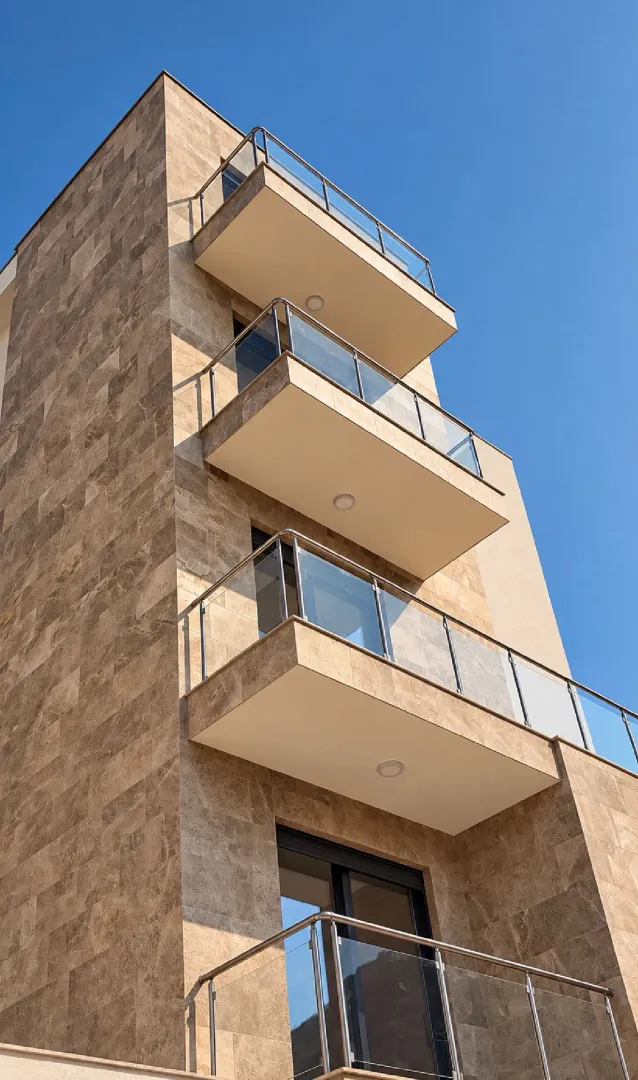 Pogled na spoljašnjost moderne stambene zgrade sa terasama i kamenom fasadom.