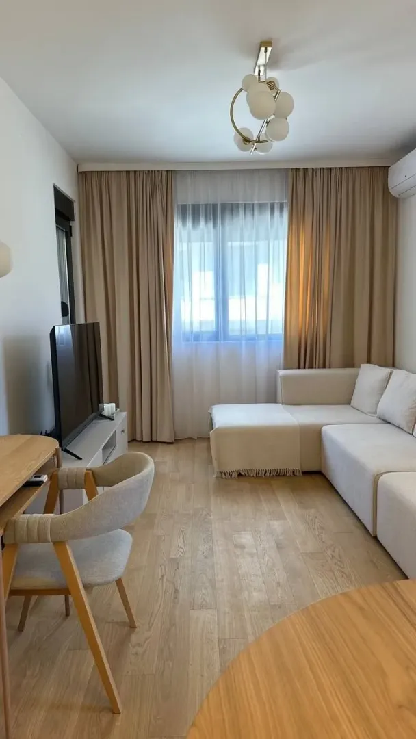 Dnevna soba sa garniturom, televizorom i trpezarijskim stolom.