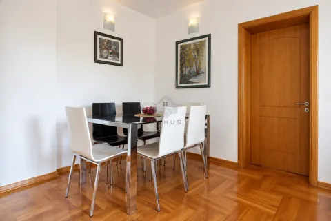 Dining area with a black glass table, white and black chairs, and wooden flooring. - image 3