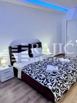 Furnished bedroom with a double bed, white nightstands, and a wardrobe. - image 9
