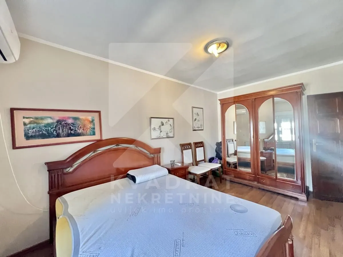 Furnished bedroom with a double bed, wooden wardrobe and wall paintings.