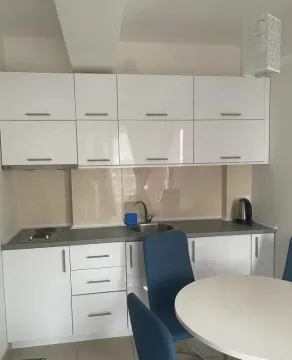 Manja kuhinja sa bijelim elementima i trpezarijskim stolom u prvom planu. - image 7