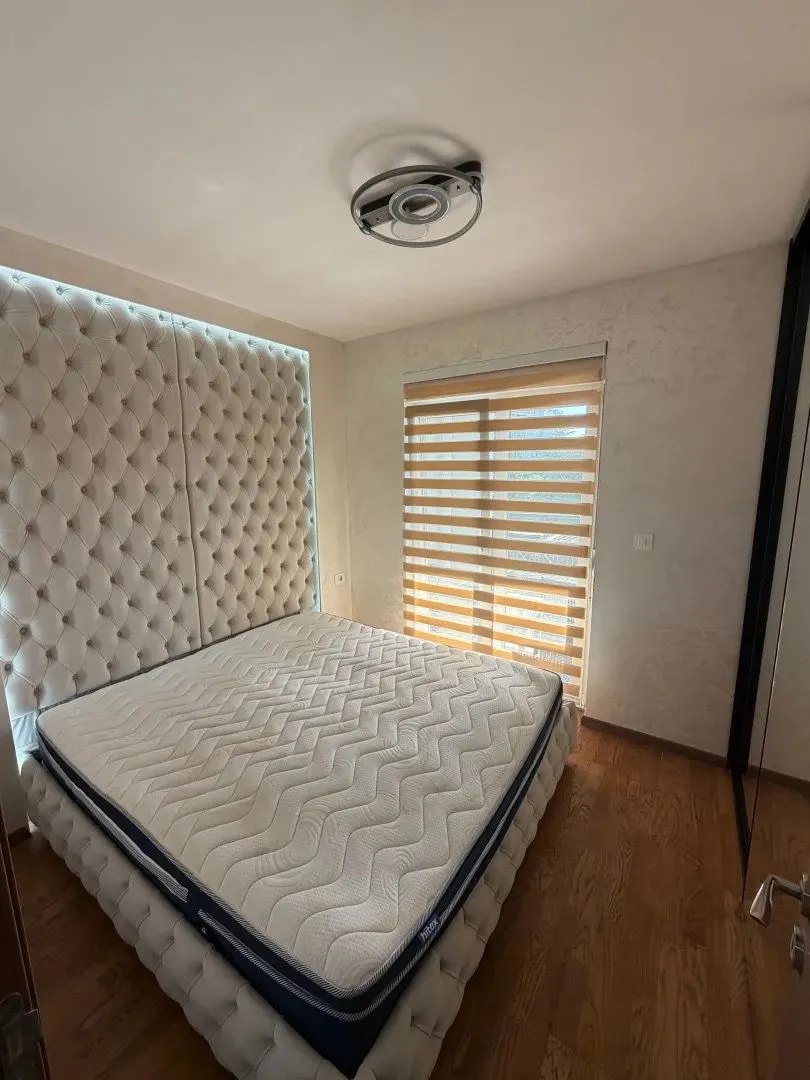 Furnished bedroom with a large double bed and a window.