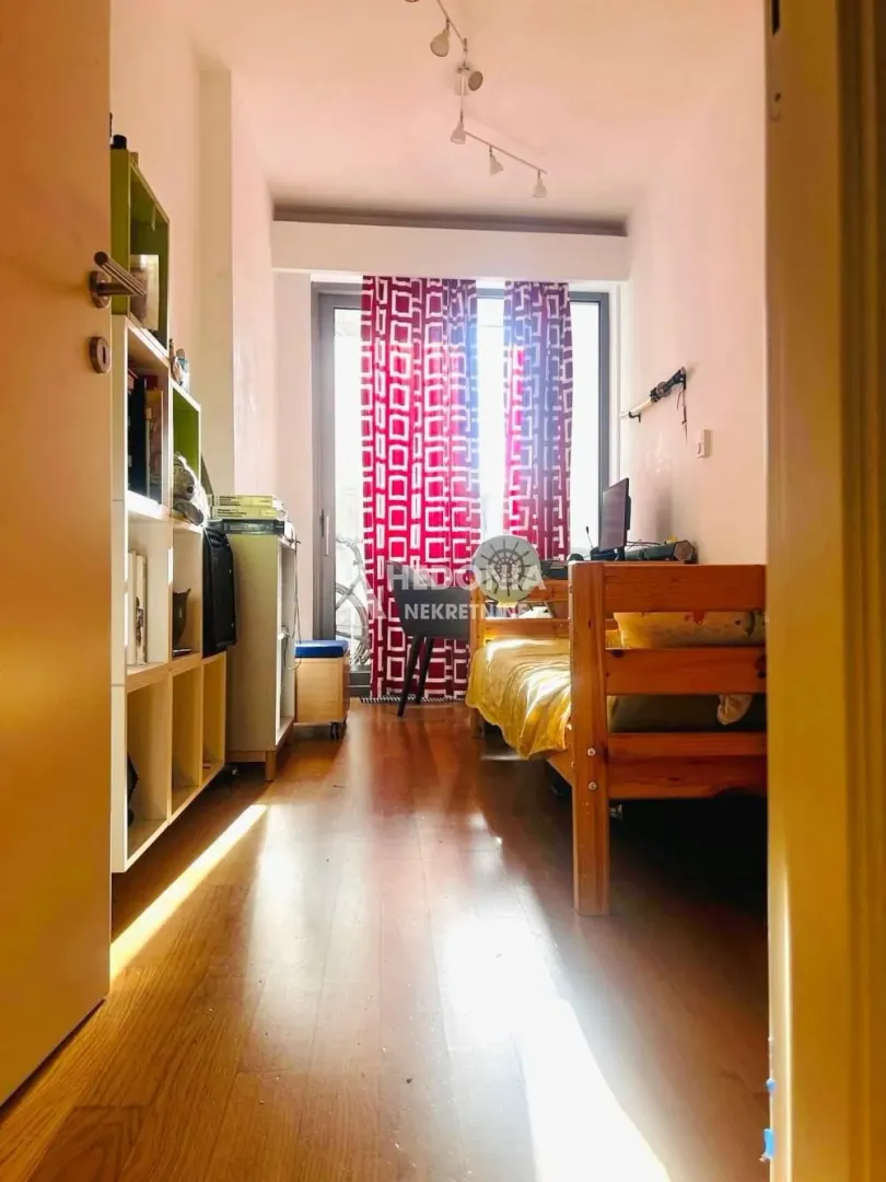 Manja spavaća soba sa krevetom, radnim stolom i policama za knjige.