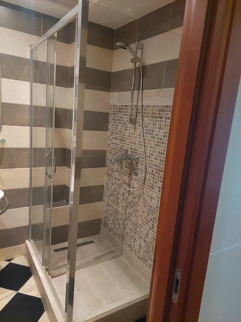 Kupatilo sa tuš kabinom i mozaik pločicama.