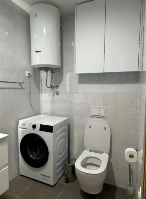 Bathroom equipped with a toilet, washing machine, and water heater.