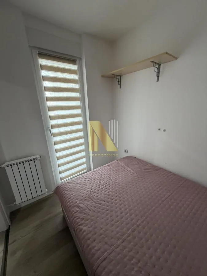 Manja spavaća soba sa krevetom i prozorom.