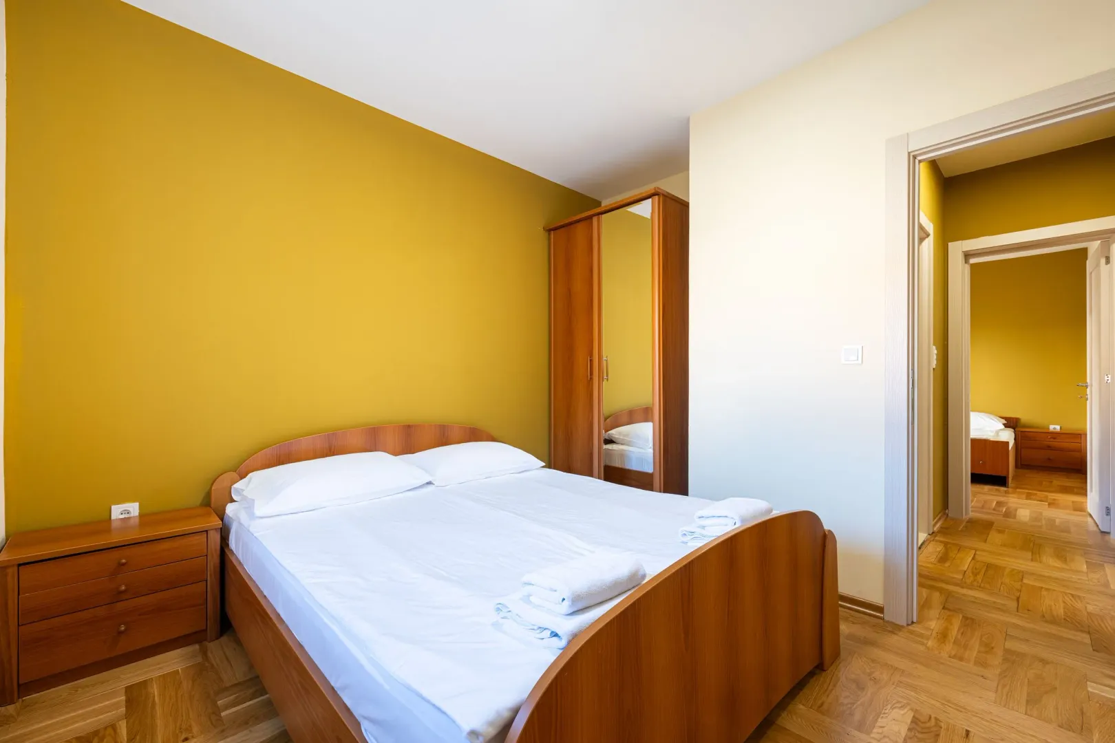 Furnished bedroom with a double bed and a wooden wardrobe.