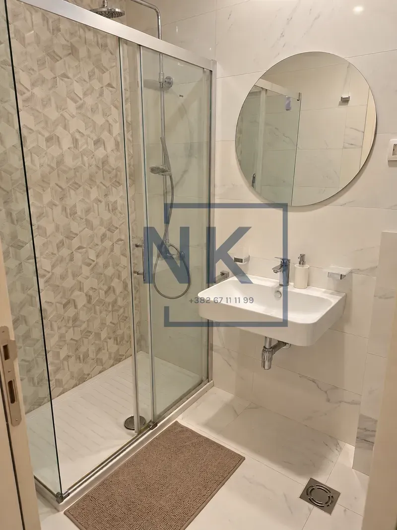 Moderne kupatilo sa tuš kabinom i umivaonikom.