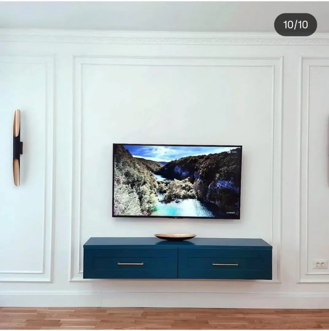 Dnevna soba sa zidom ukrašenim lajsnama i modernom plavom komodom.