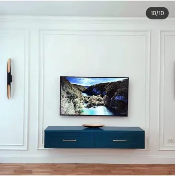 Dnevna soba sa zidom ukrašenim lajsnama i modernom plavom komodom. - image 3