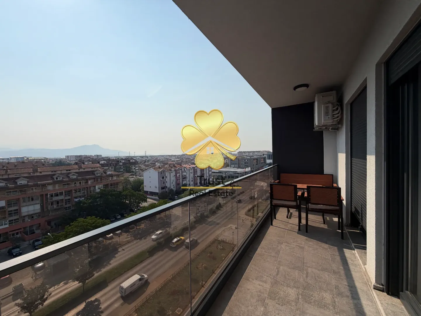 Spacious balcony with seating furniture and a city view.