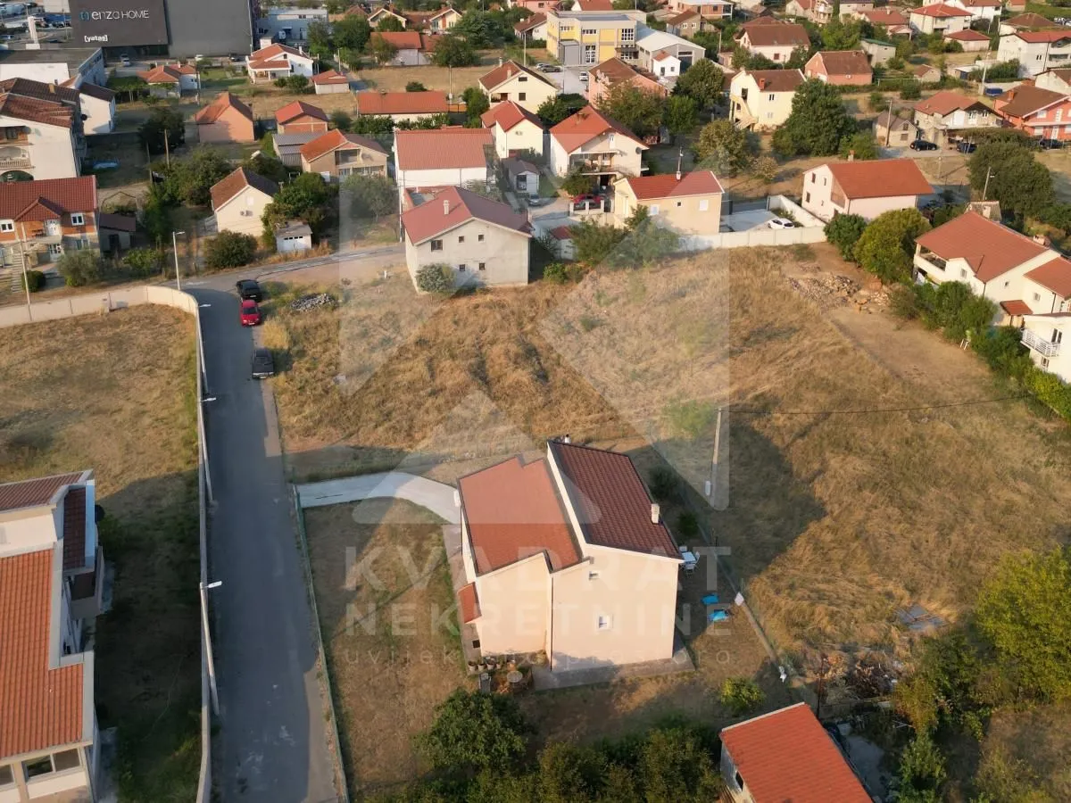 Pogled iz vazduha na plac sa kućom i okolno naselje.