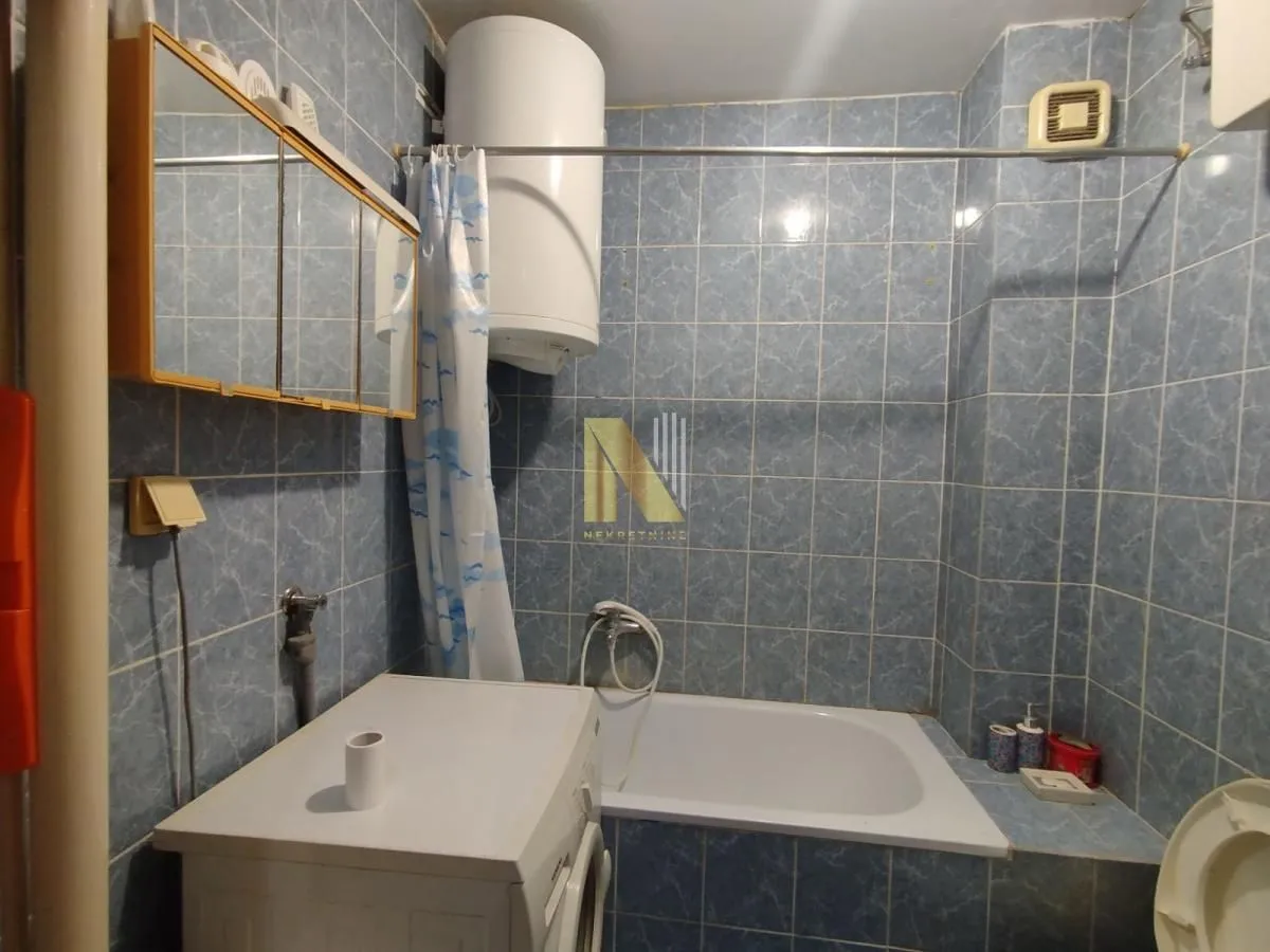 Manje kupatilo sa pločicama, kadom i veš mašinom.