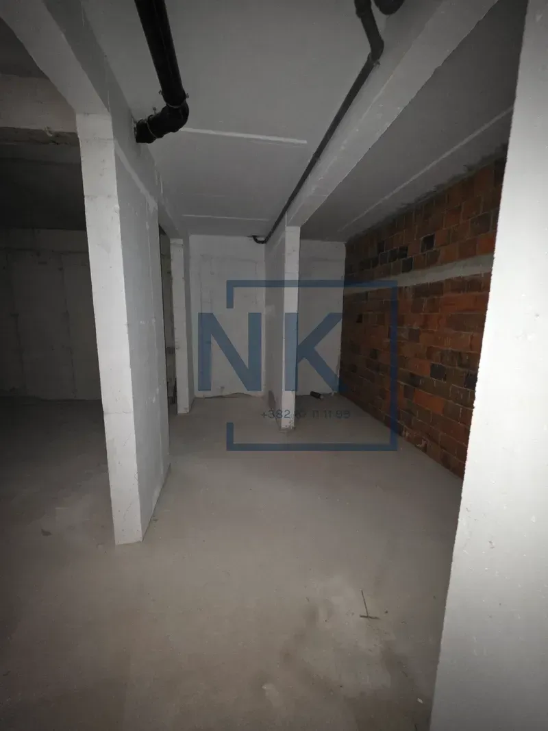 Unfinished space in gray phase of construction with pillars and installations.