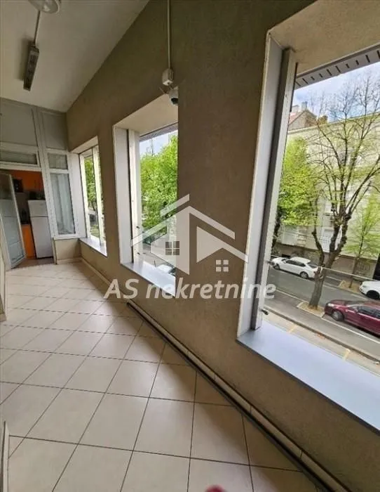 Zastakljeni balkon sa keramičkim pločicama i pogledom na ulicu.