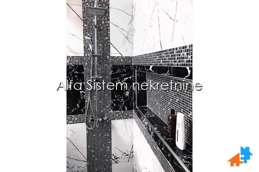 Tuš kabina sa crnim i belim pločicama i ugradnom nišom.
