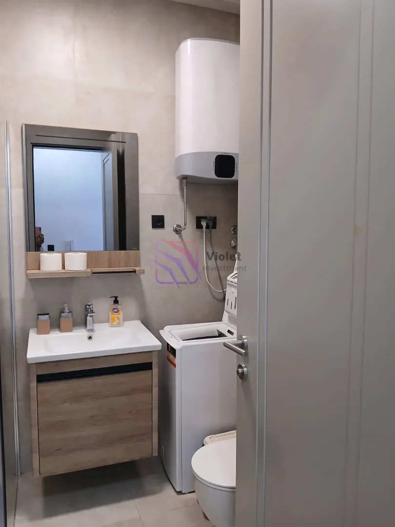 Manje kupatilo sa umivaonikom, veš mašinom, WC šoljom i bojlerom.