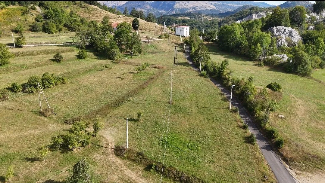 Pogled iz vazduha na prostrano zemljište sa putem i rastinjem.