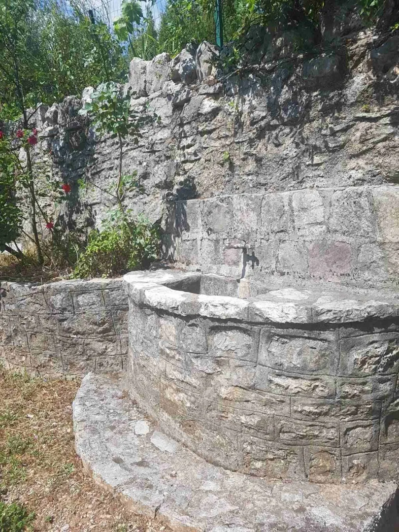 Stone yard detail with a water fountain and a natural stone wall.