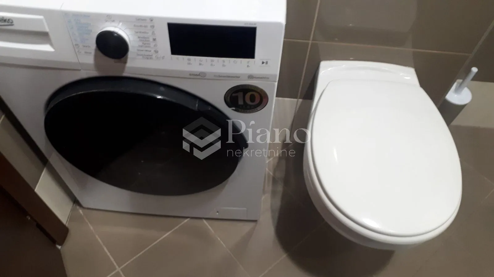 Bathroom with a washing machine and toilet.