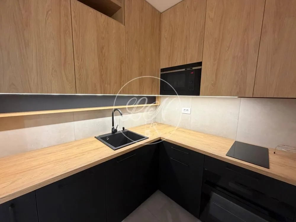Kitchen with wooden upper cabinets, black lower cabinets, and built-in appliances.
