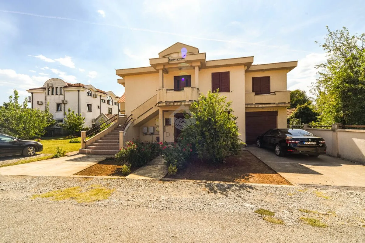 Front view of a multi-story house with a landscaped yard and parking space.