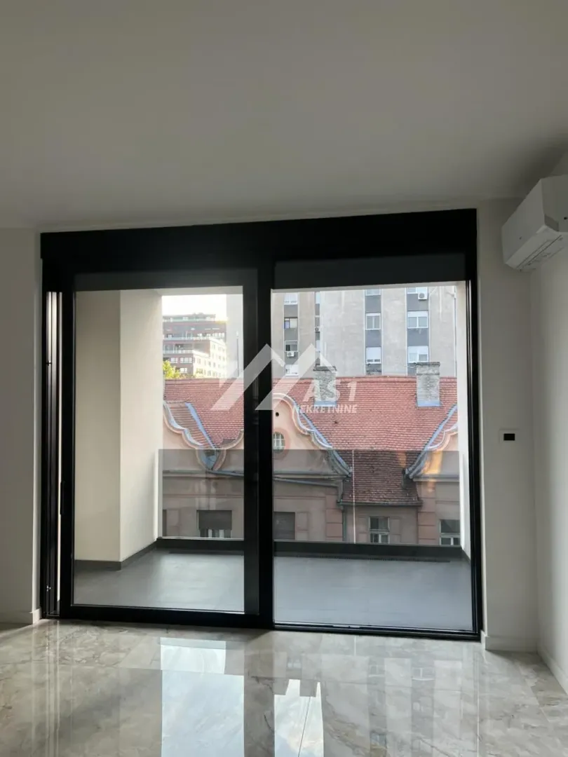 View through large glass doors to the terrace and surrounding buildings.