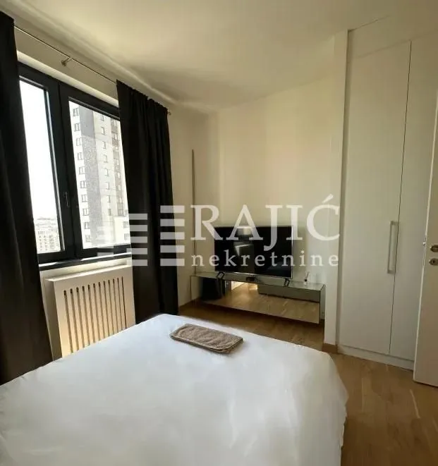 Furnished bedroom with a double bed, wardrobe, and TV.