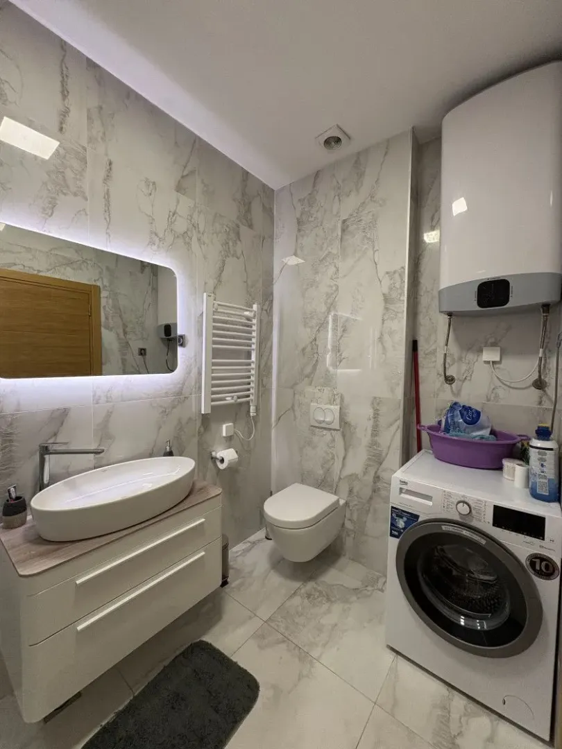 Moderne kupatilo sa umivaonikom, wc šoljom, tušem i veš mašinom.