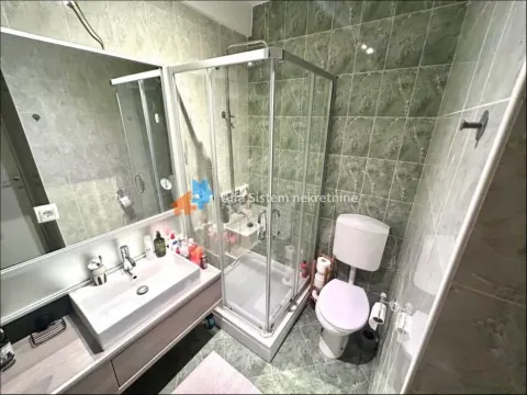 Bathroom equipped with a shower cabin, washbasin, and toilet with green ceramic tiles. - image 5