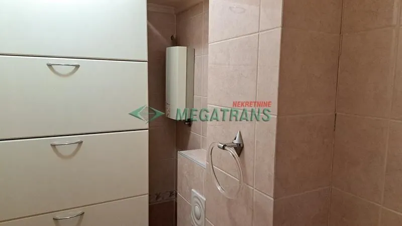 Pogled na kupatilo sa keramičkim pločicama i ugradnim elementima.