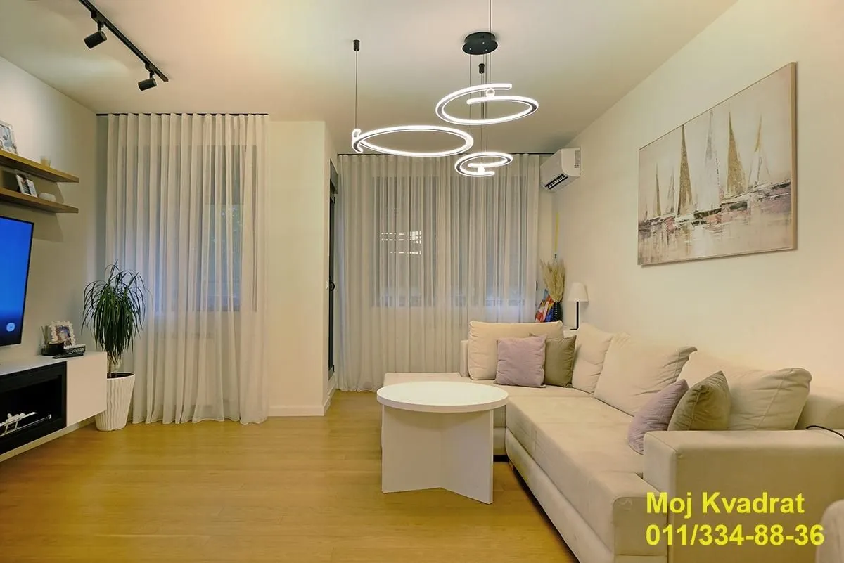 Living room with a sectional sofa, TV, and modern lighting.