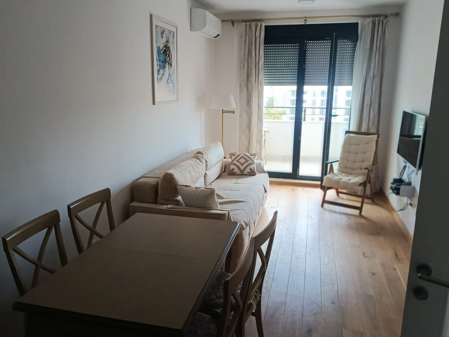 Living room with a sofa, dining table, and balcony access.