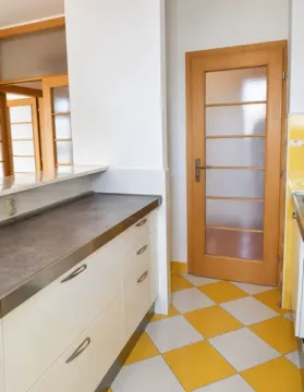 Part of the kitchen with work units, yellow and white ceramic tiles, and a wooden door. - image 8