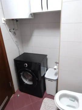 Dio kupatila sa crnom veš mašinom i bojlerom. - image 3