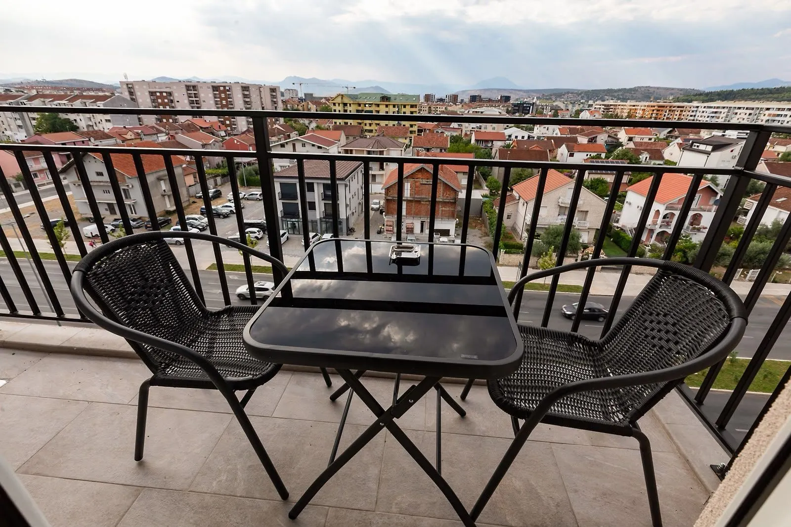 Furnished balcony with a table, two chairs, and a city view.