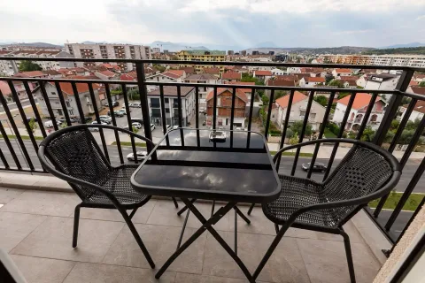 Furnished balcony with a table, two chairs, and a city view. - image 9