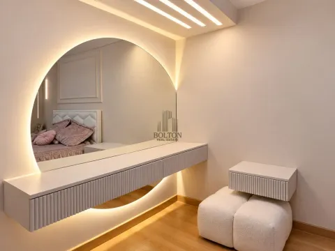 Modern vanity area with a large round backlit mirror in the bedroom. - image 7