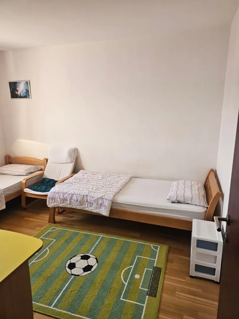 Children's bedroom with two wooden beds and a football pitch motif rug.