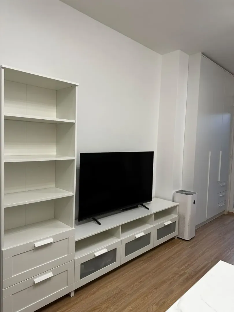 Bijeli namještaj sa televizorom i policama u dnevnoj sobi.