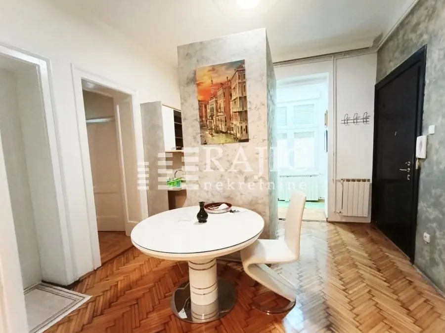 Living room with a dining table and parquet flooring.