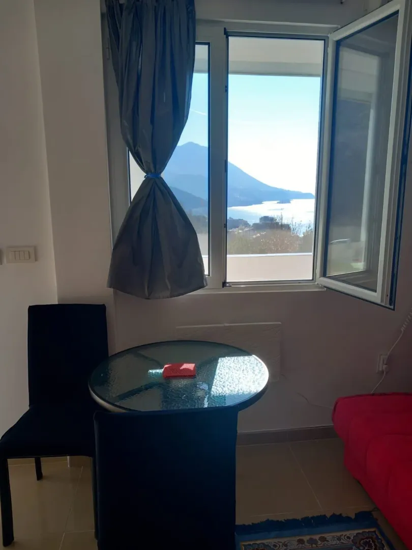Living room with a table, chairs, and a sea view through the window.