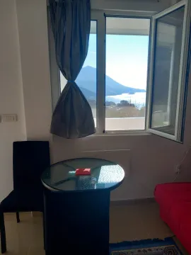 Living room with a table, chairs, and a sea view through the window. - image 8