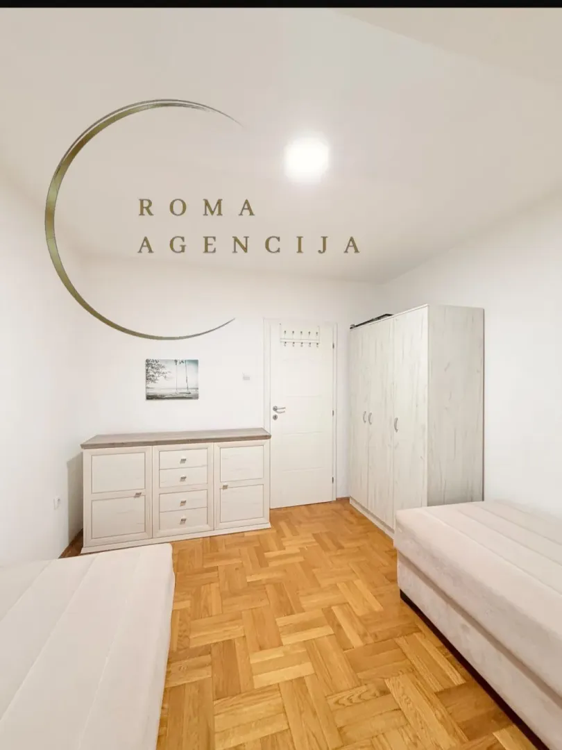 Bright bedroom with beds, wardrobe, and wooden flooring.