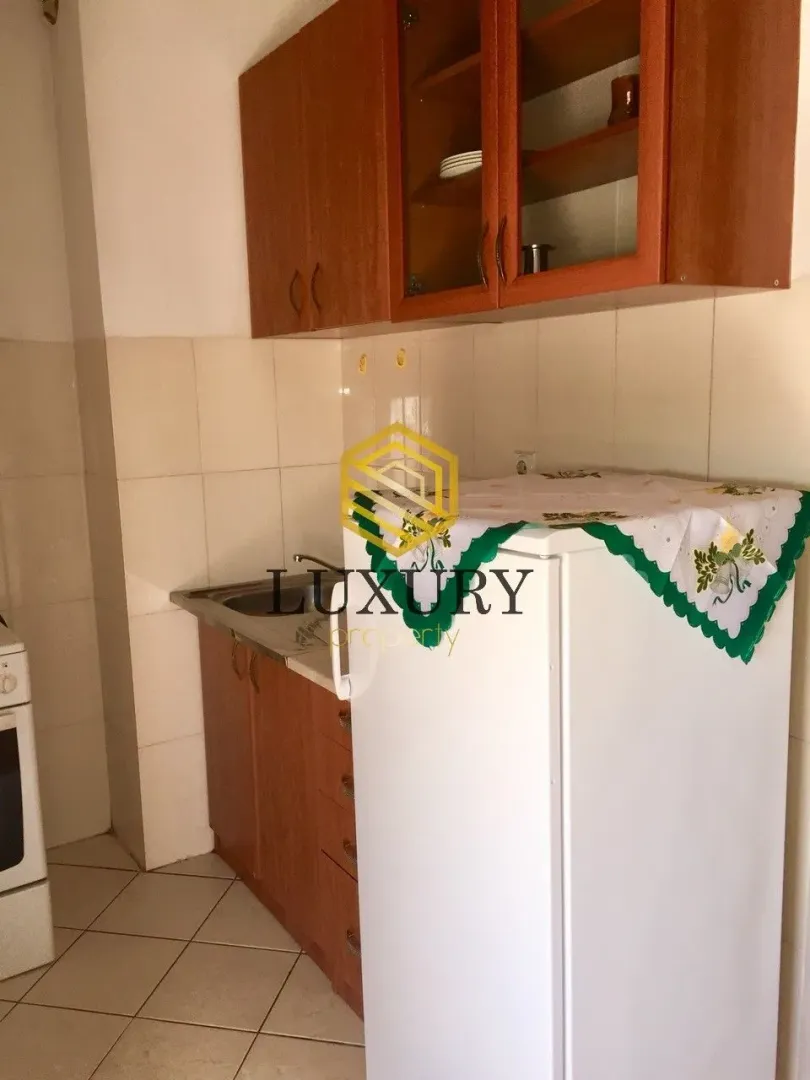 Manja kuhinja sa drvenim elementima i frižiderom.