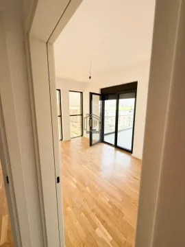 View from the hallway into an empty room with wooden flooring and access to the terrace. - image 7