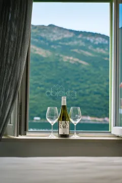 Flaša vina i čaše na prozorskoj dasci sa pogledom na planinu i more. - image 8
