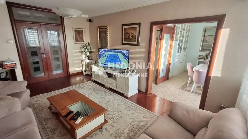 Dnevna soba sa garniturom, TV-om i pogledom na trpezariju.