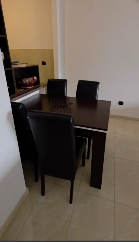 Trpezarijski sto sa crnim kožnim stolicama u dijelu dnevnog boravka.